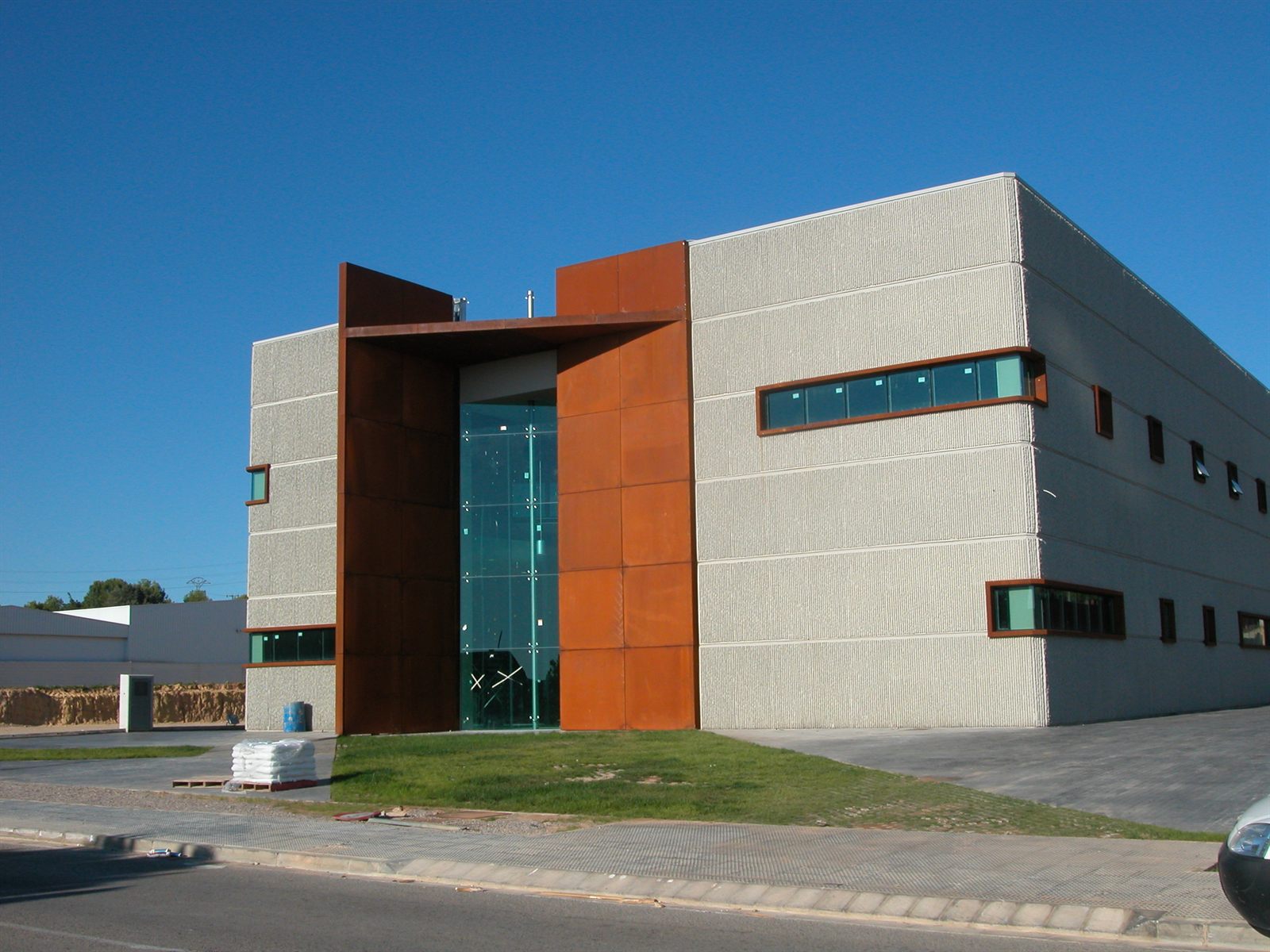 Sede de oficinas Proyex: volumen de acero corten sobre basamento acristalado